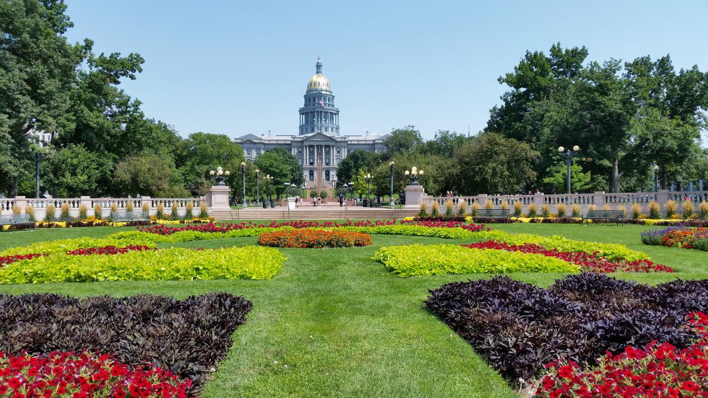 Capitol building with golden dome in the distance, with colorful flower gardens in the foreground